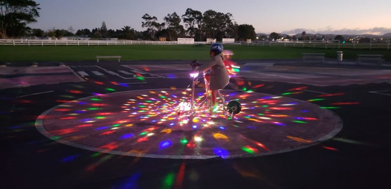 A child on a bike, surrounded by colourful lights