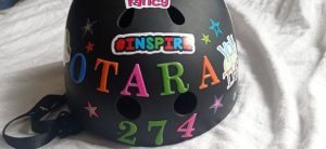 A bike helmet with stickers on it which says "Inspire Ōtara"