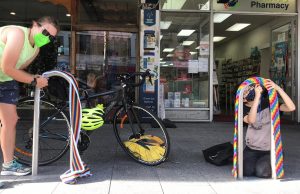 Two people put rainbow decorations on bike parks