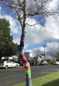 A yarnbombed tree, in rainbow colours