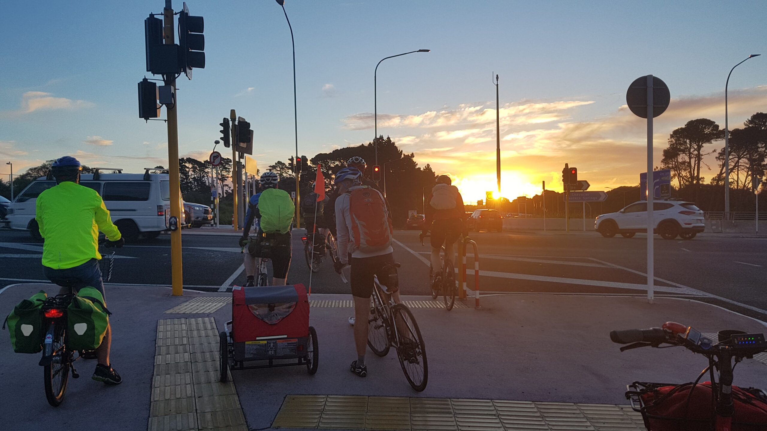 A beautiful sunset, a large number of people riding bikes at an intersection along the Northwestern.