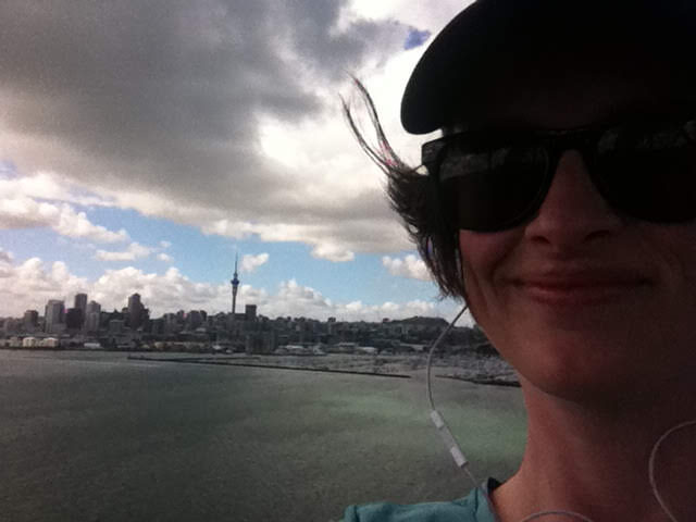 Megan smiling, hair blowing in the wind, the skytower and city in the background.