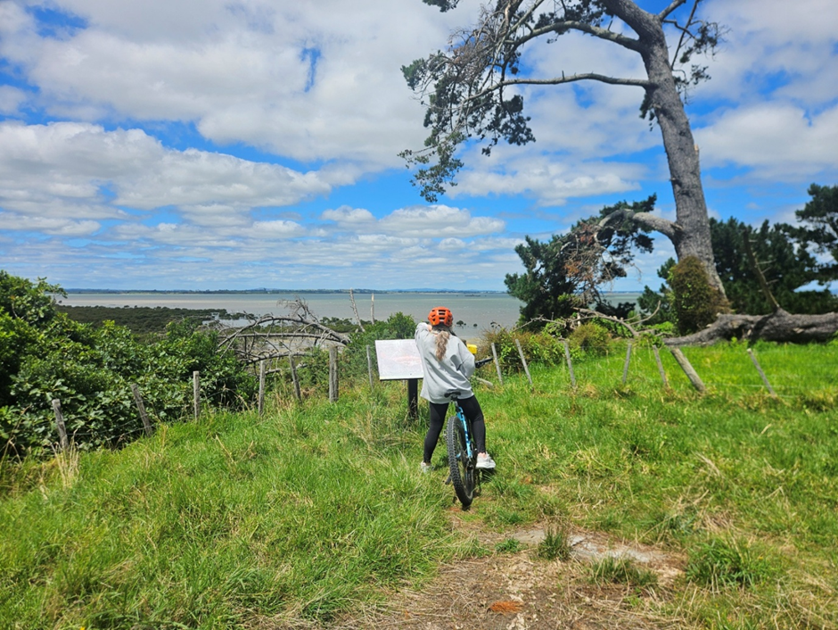 woman on a bike on a green hill overlooking a view