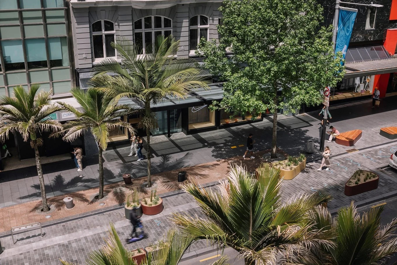 An overhead view of a peaceful looking Queen St with palms and seating areas.