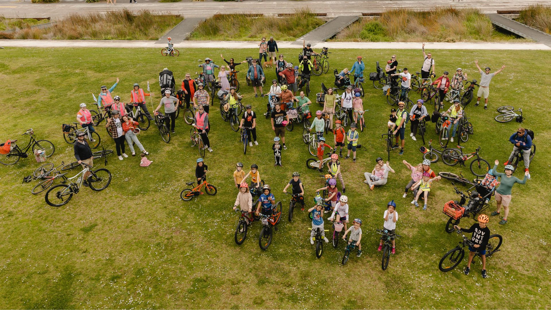 crowd of kids and adults on bikes wave up at camera