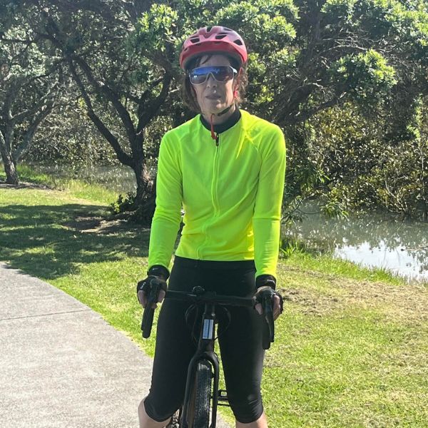 Karen is in sports gear on a bike in park