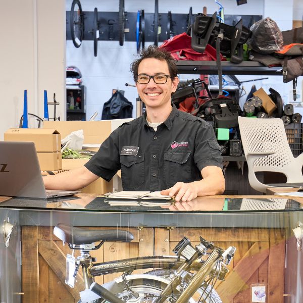 Maurice smiles from behind his bike shop front desk