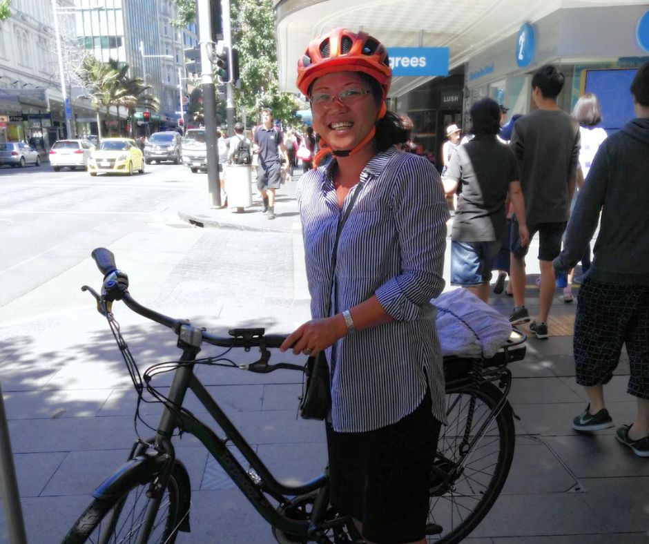 Wing stands with her bike on a retail street